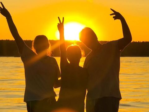 3 Jugendliche posieren vor der untergehenden Sonne.