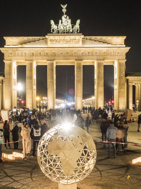 Brandenburger Tor in Berlin bei Nacht davor ein beleuchteter Globus aus Metall links das Wort Earth und rechts davon das Wort Hour