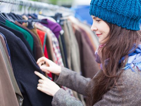 Eine Frau mit blauer Mütze betrachtet Jacken an einem Flohmarktstand