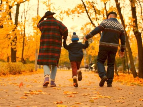 Älteres Paar geht im Herbst mit Enkel im Park spazieren 