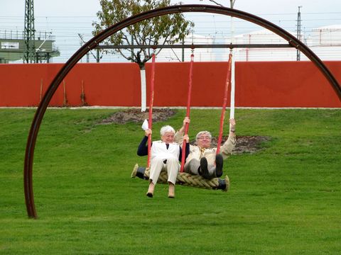 Senioren schaukeln unter einem großen Stahlbogen im Stadtgarten Moabit