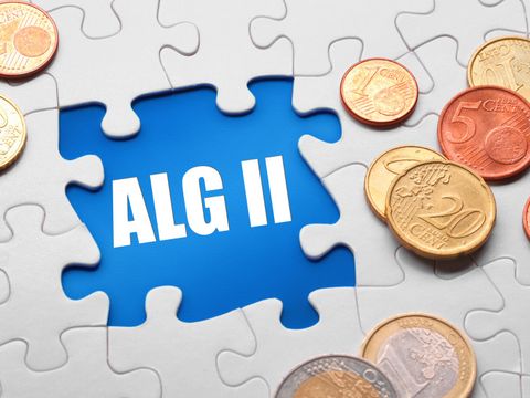 Puzzleteil mit Aufschrift ALG II und Münzen