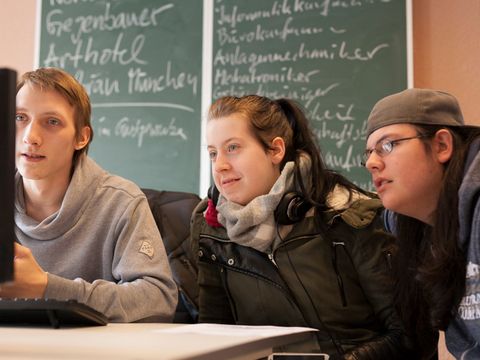Drei Jugendliche sitzen gemeinsam vor einem Computerbildschirm. Bildunterschrift: Gemeinsame Lerneinheiten zur beruflichen Qualifikation