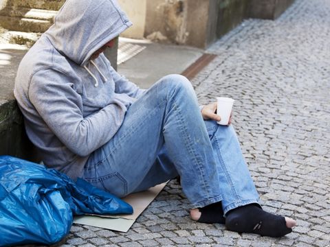 Auf Boden sitzender obdachloser Mann hofft auf Geldspende