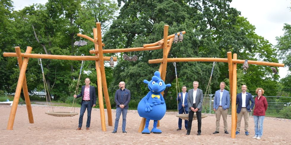 Bezirkbürgermeister Igel und Bezirksstadtrat Hölmer gemeinsam mit Theo Tintenklecks und Sponsoren an der Fledermausschaukel auf dem Weltspielplatz