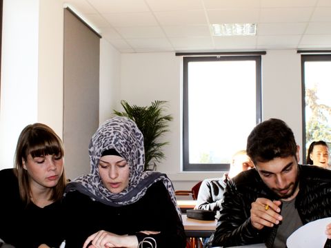 Drei Personen nehmen aktiv in Gruppenarbeit am Unterricht teil.