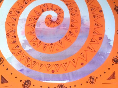 Eine aus Karton ausgeschnittene, orangefarbene Spirale auf bemaltem Papier