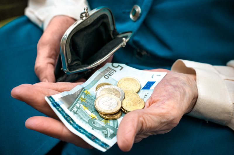 Seniorenhände halten Geld und ein Portemonnaie