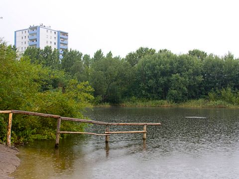 See in der Hönower Weiherkette an einem regnerischen Tag mit einem Hochhaus im Hintergrund