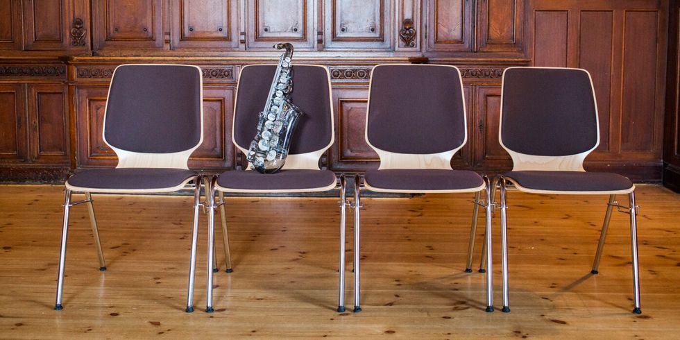 Vier Stühle, auf einem liegt ein Saxophon