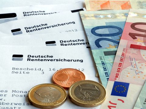 Münzen und Geldscheine liegen auf einem Bescheid der Deutschen Rentenversicherung