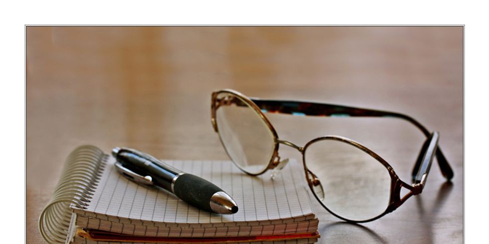 Eine Brille auf einem Schreibblock mit Kugelschreiber
