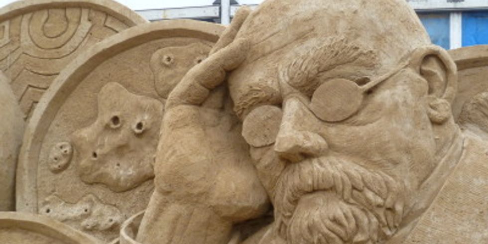 Die Sandskulptur stellt Robert Koch mit Viren und Bakterien dar