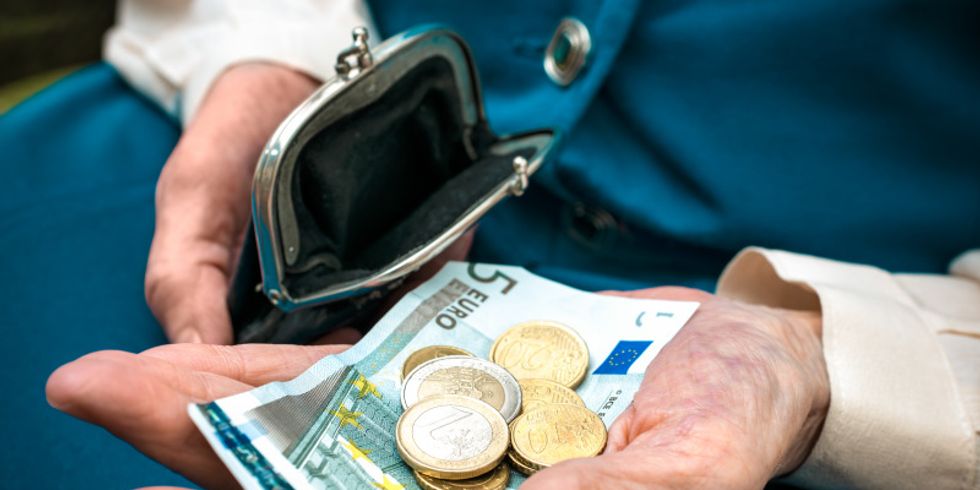 Seniorenhände halten Geld und ein Portemonnaie