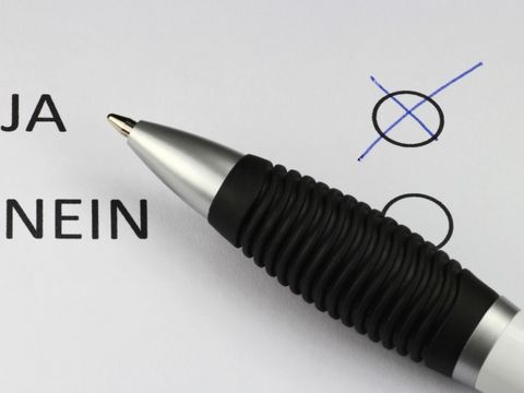 Kugelschreiber auf einem Blatt Papier mit dem Ankreuzfeldern Ja und Nein