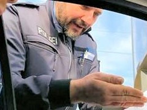 Polizeibeamter zeigt einem Bürger an einer Autotür Informationen