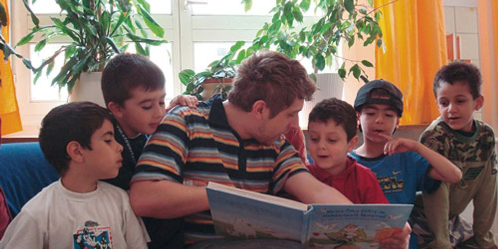 Ein Mann liest mit mehreren Kindern ein Buch