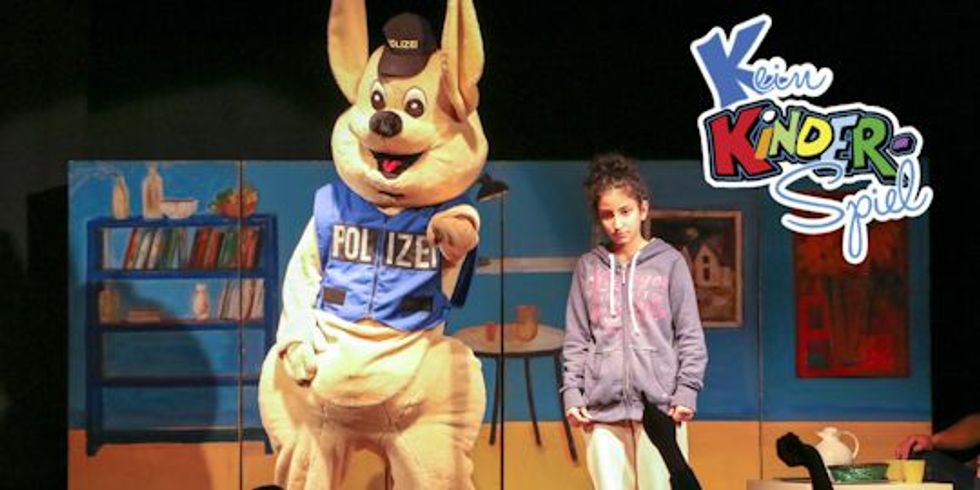 Polizeihase Huggy mit einem Mädchen auf der Bühne sowie oben rechts das Logo Kein Kinderspiel