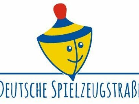 Logo der Deutschen Spielzeugstraße blau-gelb gestreifter Kreisel mit rotem Griff
