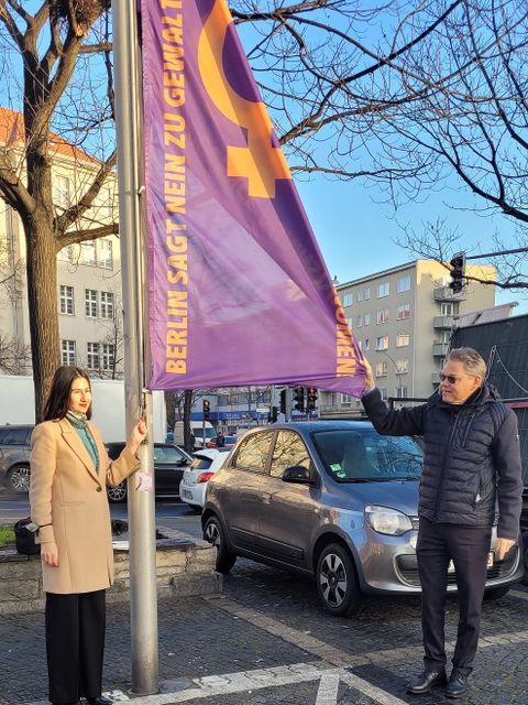 Frau und Mann am Fahnenmast zeigen Flagge