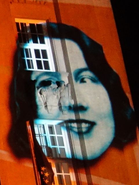 das Porträt einer Frau, das an eine Häuserwand projiziert wird