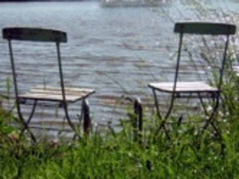 2 Stühle stehen an einem Gewässer in der Sonne