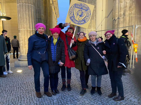 Frauen des Soroptimist International Club Berlin Charlottenburg stehen bei der Veranstaltung One Billion Rising 2023 vor dem Brandenburger Tor.