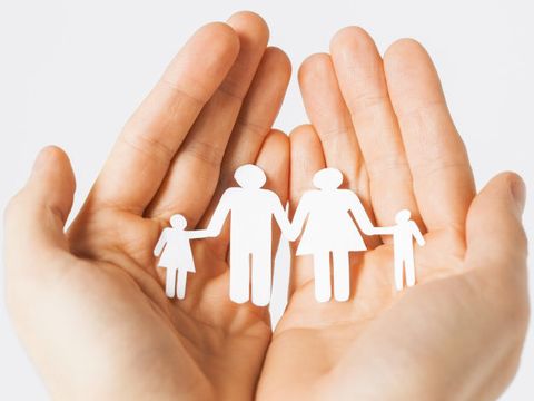 Bildausschnitt: Hände halten schützend Scherenschnitt von einer Familie