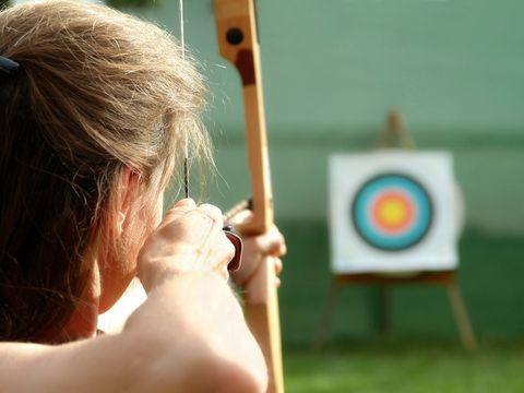 Eine Frau beim Bogenschießen zielt auf die Zielscheibe