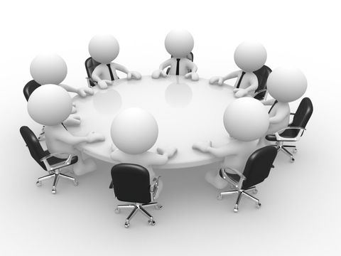 Acht Personen sitzen an einem runden Tisch 