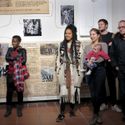 Bildvergrößerung: Menschen, die einer Rede zuhören, im Vordergrund die Künstlerinnen Nathalie Anguezomo Mba Bikoro & Anais Héraud-Louisadat