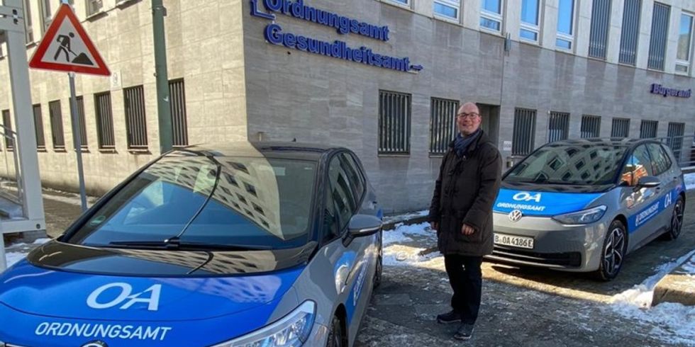 Bezirksstadtrat Arne Herz mit neuen E-Autos vor dem Dienstgebäude am Hohenzollerndamm