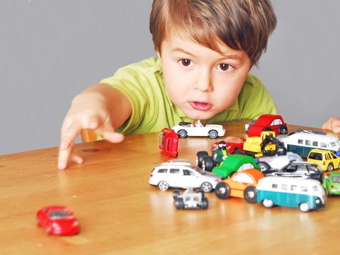 Ein kleiner Junge spielt mit vielen Autos am Tisch
