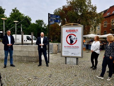 Bildvergrößerung: Stadträte Stephan Machulik und Stadtrat Frank Bewig (von links nach rechts) stehen vor dem Kampagnenplakat am U-Bahnhof Rathaus Spandau