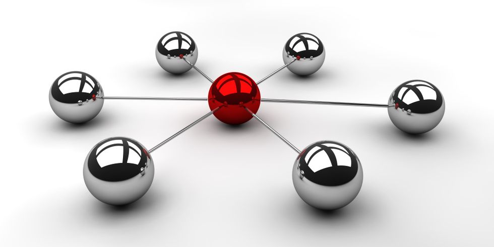 Sechs Kugeln aus Chrom kreisförmig mit einer roten Kugel in der Mitte angeordnet