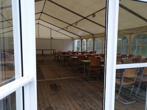Bildvergrößerung: Blick in das Zelt, was für die Versorgung der Schülerinnen und Schülern mit Schulessen mit Tischen und Stühlen ausgestattet ist