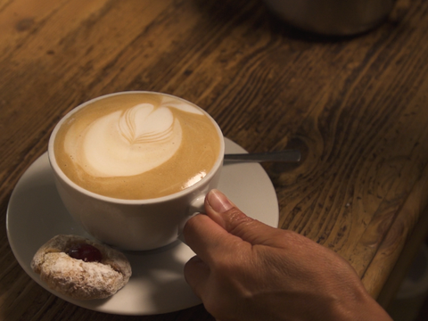 Zu sehen ist ein Kaffee mit einem Keks im Pausini Café