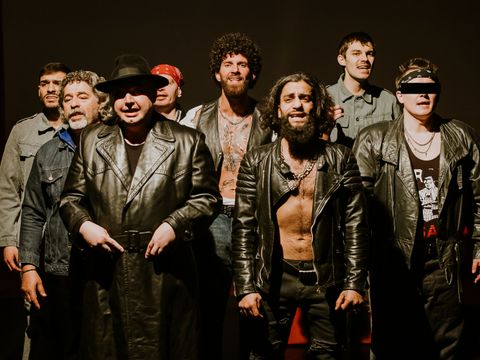 acht Männer stehen auf einer Theaterbühne