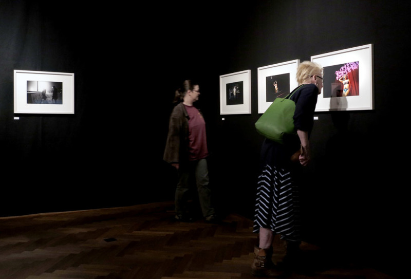Blick in die Ausstellung mit einer Fotoserie auf schwarzen Wänden