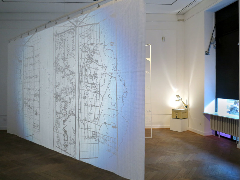  Ein Raum wird durch eine Leinwand geteilt, auf die mit einem Overhead-Projektor Landkarten projiziert sind