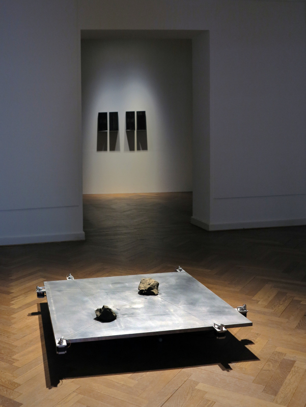 Blick in die Ausstellung mit einer scheinbar schwebenden Metallplatte im Vordergrund