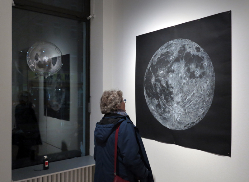 Eine Besucherin betrachtet eine Zeichnung mit einem weißen Mond auf schwarzem Grund.