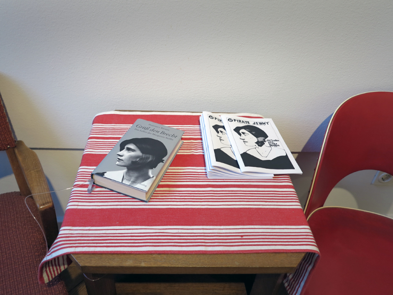 Auf dem Tisch in einer kleinen Sitzecke liegen die Zeitung "Pirate Jenny" und das Buch "Grüß den Brecht. Das Leben der Margarete Steffin" von Hartmut Reiber.