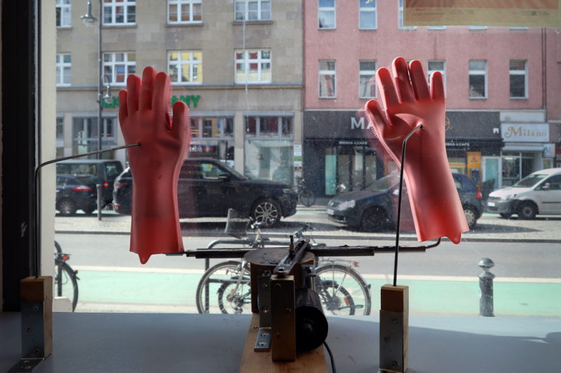 Zwei pinke Putzhandschuhe an einer Installation am Fenster mit Blick auf die Karl-Marx-Straße 