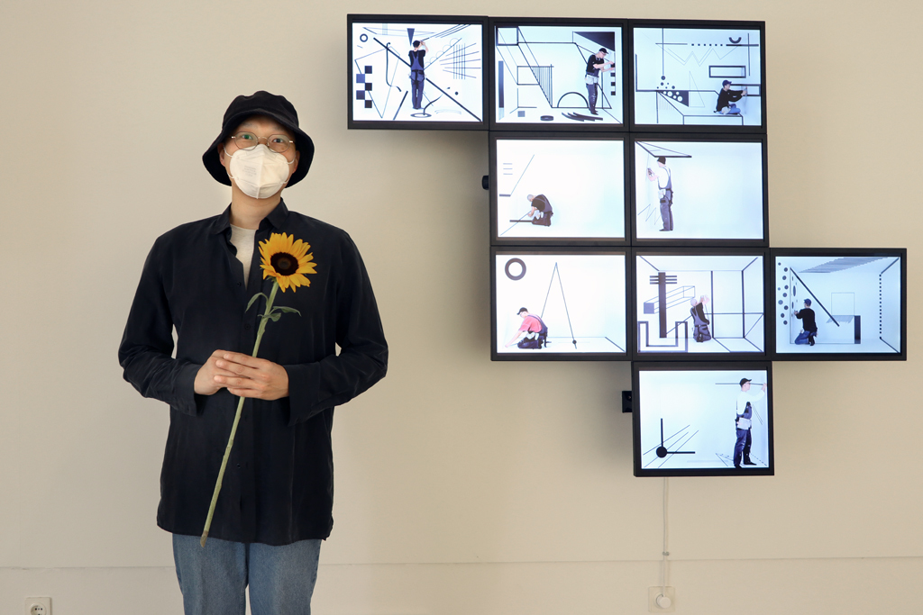 Hyunho Park vor ihrem Werk: Time Crystals - Neun Räume, 2019, BU: Hyunho Park: Time Crystals - Neun Räume, 2019 Auf der rechten Seite des Bildes hängen 9 Monitore an der Wand .