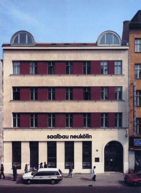 Fassade des vierstöckigen Gebäudes in der Karl-Marx-Straße 141 mit der Aufschrift "Saalbau Neukölln" über dem Eingang im Erdgeschoss.