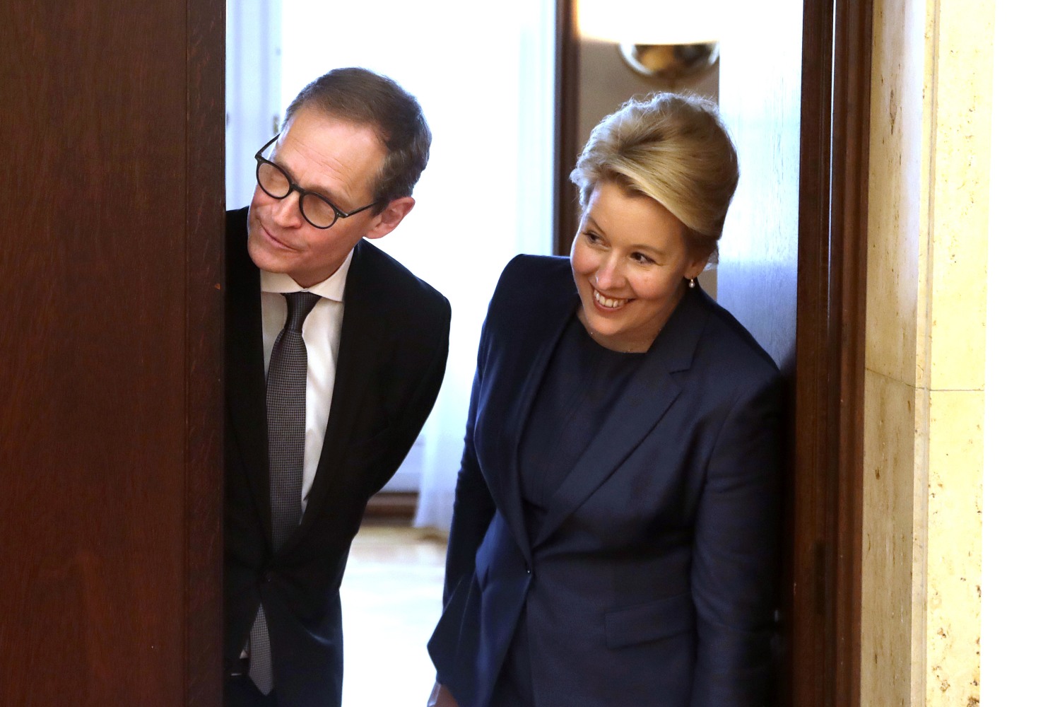 Michael Müller und Franziska Giffey blicken aus der Tür des Amtszimmers im Roten Rathaus