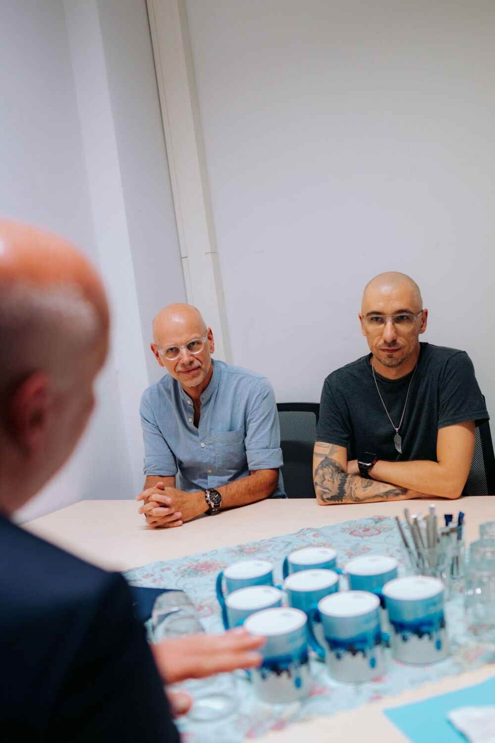 Kai Wegner und Mitarbeitende des Bürgeramts Schöneberg sitzen an einem Tisch und sprechen miteinander.