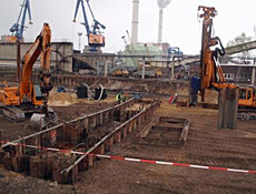 Tiefenenttrümmerung und Bodenaustausch im Bereich der Generatorgasanlage, vier Bagger auf einem Gelände, im Hintergrund Industrietürme