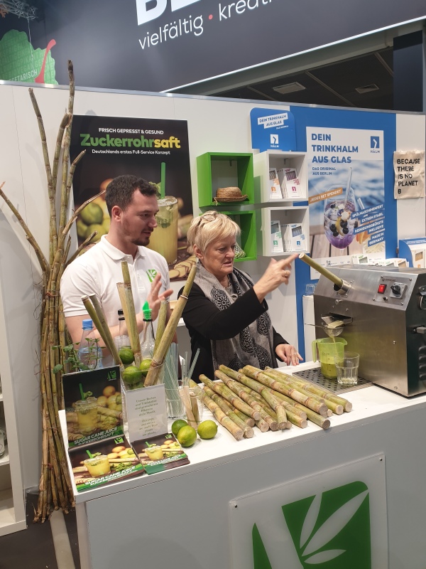 Renate Künast bedient Zuckerrohrpresse am Stand von Super Cane